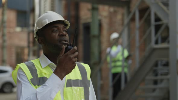 Contractor in Hardhat Using Walkie Talkie Outdoors