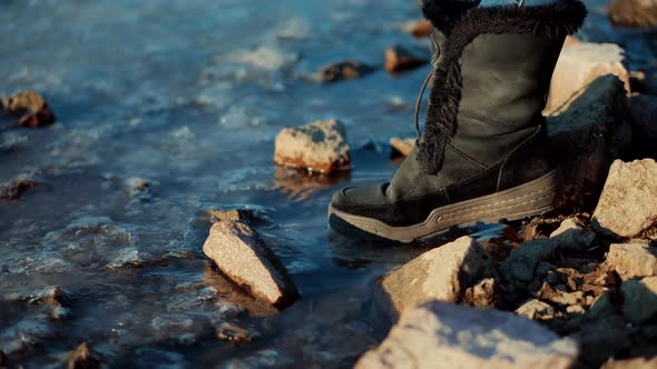 Winter Holiday Travel Weekend. Female In Warm Leather Winter Boots. Foot Steps On Frozen River.