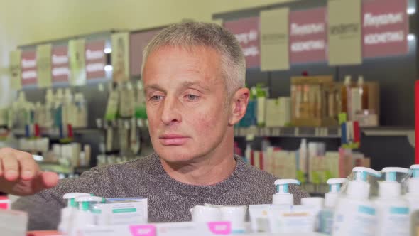 Mature Man Shopping at the Drugstore Examining Products on a Shelf