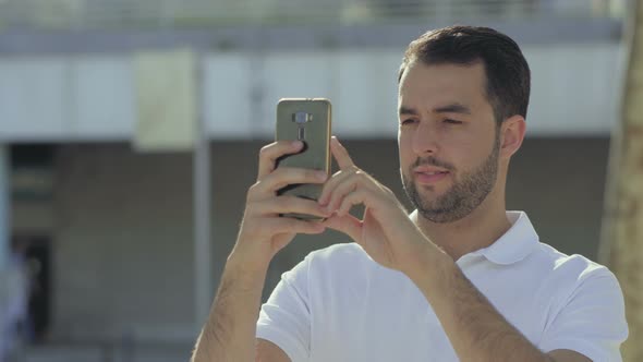 Smiling Bearded Man Holding Smartphone and Looking at Camera