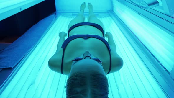 Sun Treatments in a Horizontal Solarium Female Takes a Sun Bath in a Solarium Blue Light