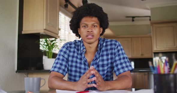 Serious african american man gesturing on video call in kitchen