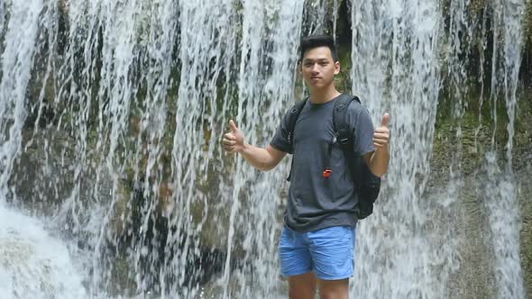 Man Standing In Front Of  Waterfall With Thumps Up