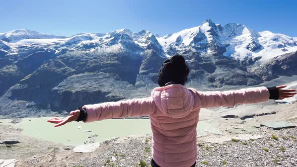 Back View of a Young Girl Embracing Fresh Air with Mountains Covered By Snow in Summer Season