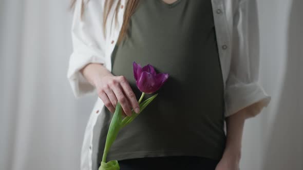 Pregnant Woman with Purple Tulip Standing Indoors Front View