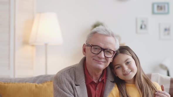 Happy Grandfather and Granddaughter Posing Together on Couch