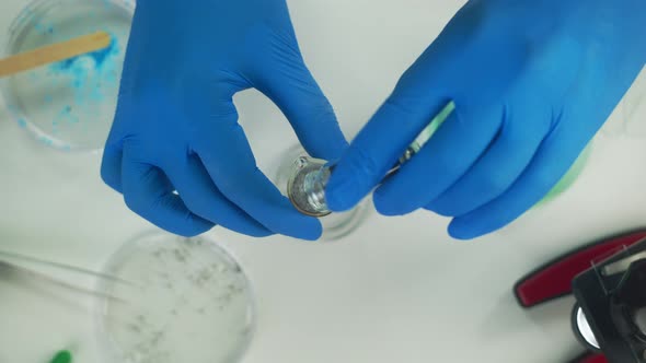 Doctor Wearing Medical Protective Gloves Working in Modern Laboratory Mixing Powder in Flask Top