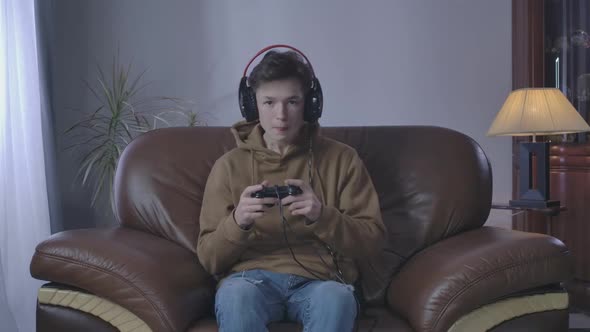 Dissatisfied Boy Losing in Video Game. Portrait of Caucasian Teenager Playing at Home on Weekends