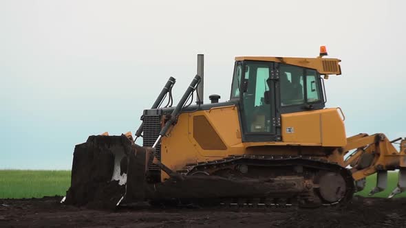 Yellow Bulldozer Rides on the Ground