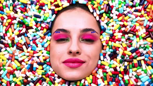 Beautiful girl acting inside a colored background made with pills