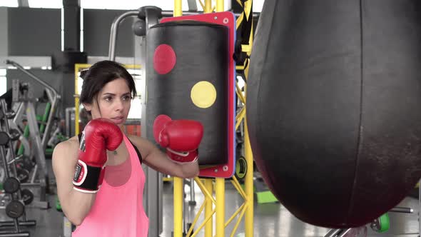 Young Inexperienced Woman Boxer Beats a Punching Bag