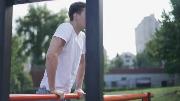 Confident Young Sportsman Working Out on Gymnastic Set in Summer Spring Park