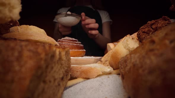 Hands of a Baker Pouring Sugar Powder on Freshly Baked Sweet Bun
