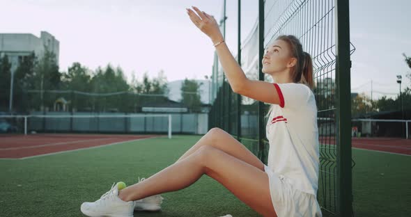 Pretty Lady Sitting Down on the Tennis