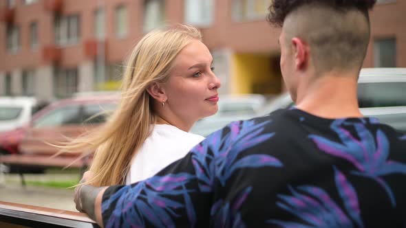 A young couple sits on a bench in the city and communicates, kisses