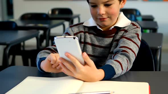 Schoolboy using mobile phone in classroom 4k