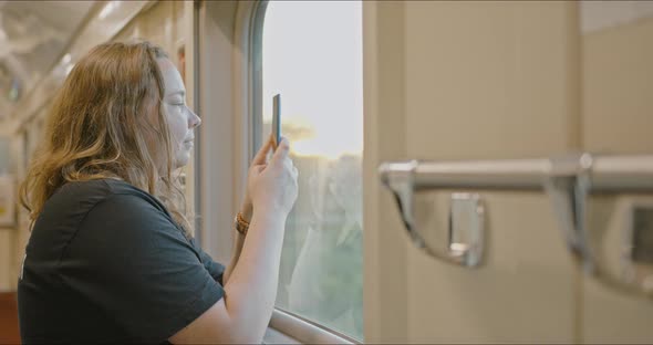 A Young Plump Girl Happily Looks Out the Train Window