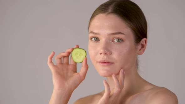 Young healthy girl with green cucumber slices