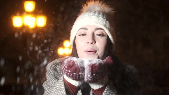 Happy Young Woman Blowing Snow at Winter Fair