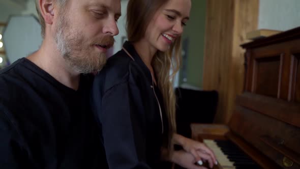 A Beautiful Married Couple Play the Piano Together in Their Beautiful Apartment, They Gently Hug and