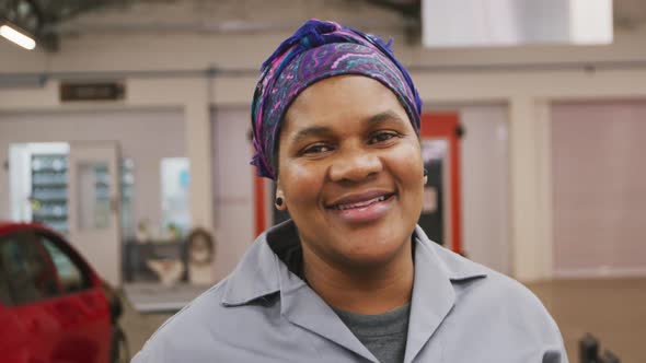 African American female car mechanic looking at the camera and smiling