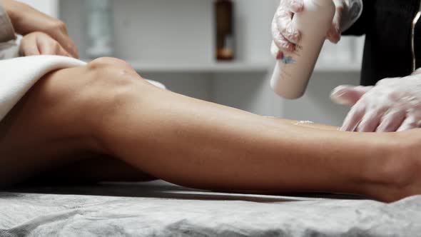 Pouring Antiseptic Powder on the Depilated Leg of the Female Client