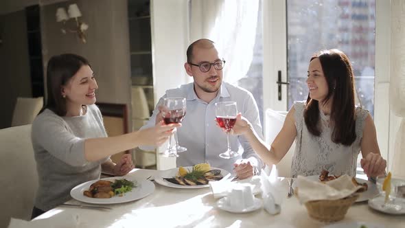 Male in the Company of Two Charming Ladies at the Restaurant Offers to Raise a Glass with Red Wine