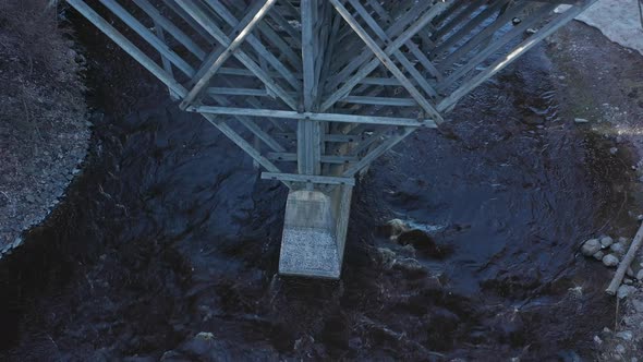 Idyllic Aerial Shot of a River with a Wooden Bridge Crossing It