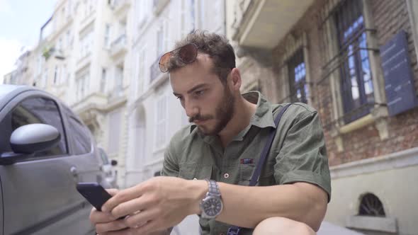 Young man looking at the phone on the street.