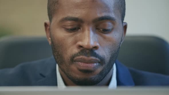 Face of Successful African American Businessman Surfing Internet on Laptop in Office and Smiling