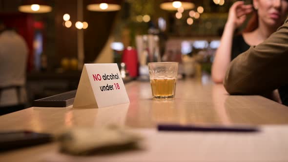 A sign with an age limit for the sale of alcohol is on the bar