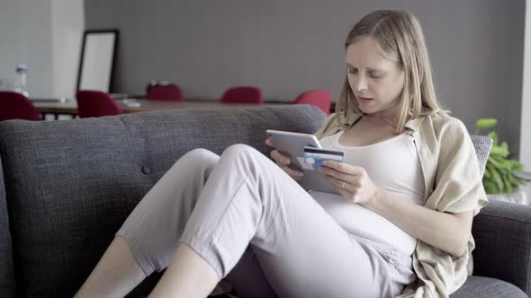 Focused Pregnant Woman Shopping Online with Tablet