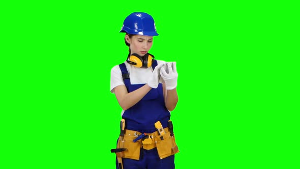 Girl Builder Looks at Her Smartphone Photo Buildings for Future Work, Green Screen