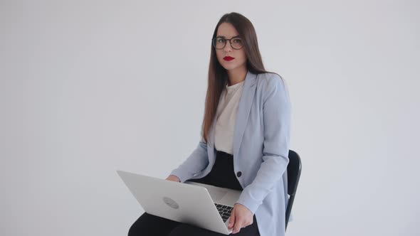 Young Successful Business Woman is Working on a Laptop and Looking at the Camera Smiling