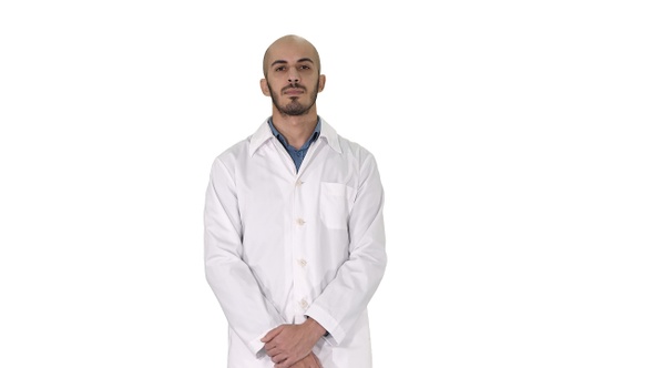 Standing young serious arab doctor on white background.