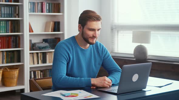 Young smiling man at laptop in office