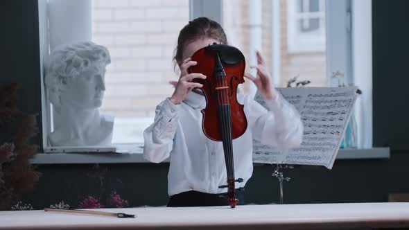 A Little Girl Puts the Violin Under Her Chin and Looking in the Camera