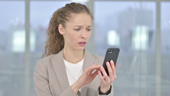 Portrait of Young Businesswoman Reacting To Loss on Smartphone
