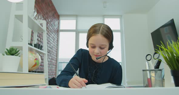 Cute Girl School Kid Child Wearing Headphones Distance Learning Online Talking To Camera