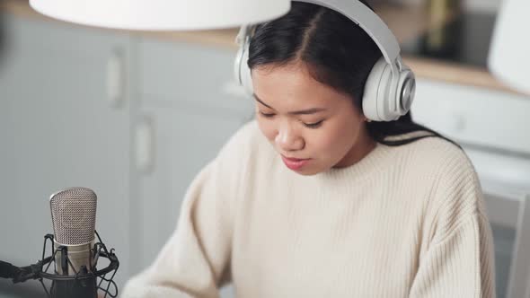 Portrait of a Asian Female Streamer in the Headphones Woman Makes a Live Podcast for Social Networks