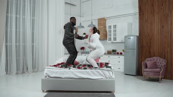 Funny Multiethnic Couple Enjoying Dancing on Bed