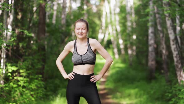 Beautiful Young Woman with a Sports Figure Goes in for Sports in the Park Stretching Herself and