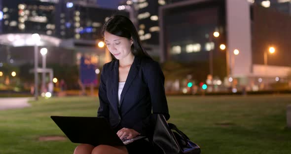 Young business woman typing on notebook computer at night