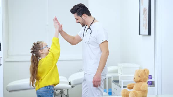 Positive Cheerful Doctor and Patient Giving Highfive Standing in Hospital Ward