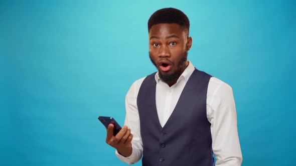 Surprised Black Man Reading a Message on His Phone