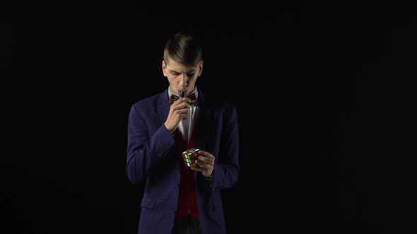 Serious Boy in Suit Is Solving Rubik's Cube in Dark.