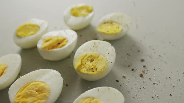 Video of close up of peppered halves of hard boiled eggs on grey background