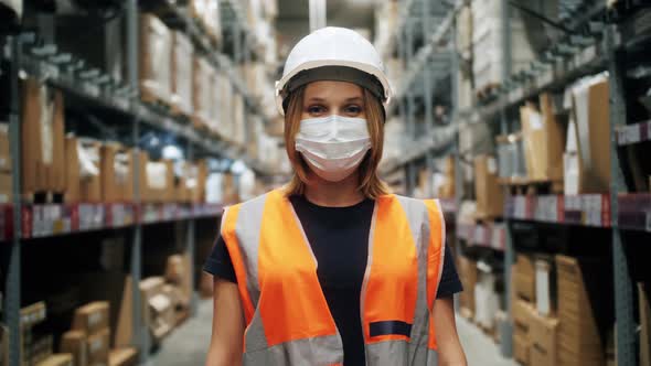 Professional Female Worker of Warehouse Wearing Protective Medical Mask Safety Vest and Hard Hat on