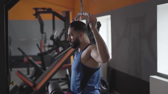 Side View of Muscular Middle Eastern Sportsman Using Shoulder Pull Down Machine in Gym. Strong