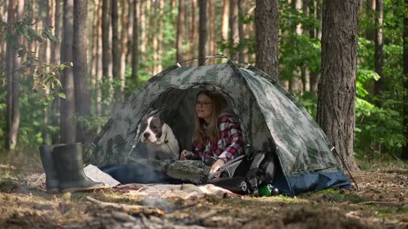 Relaxed Woman Opening Unzipping Camp Tent Stretching in the Morning in Forest with Dog